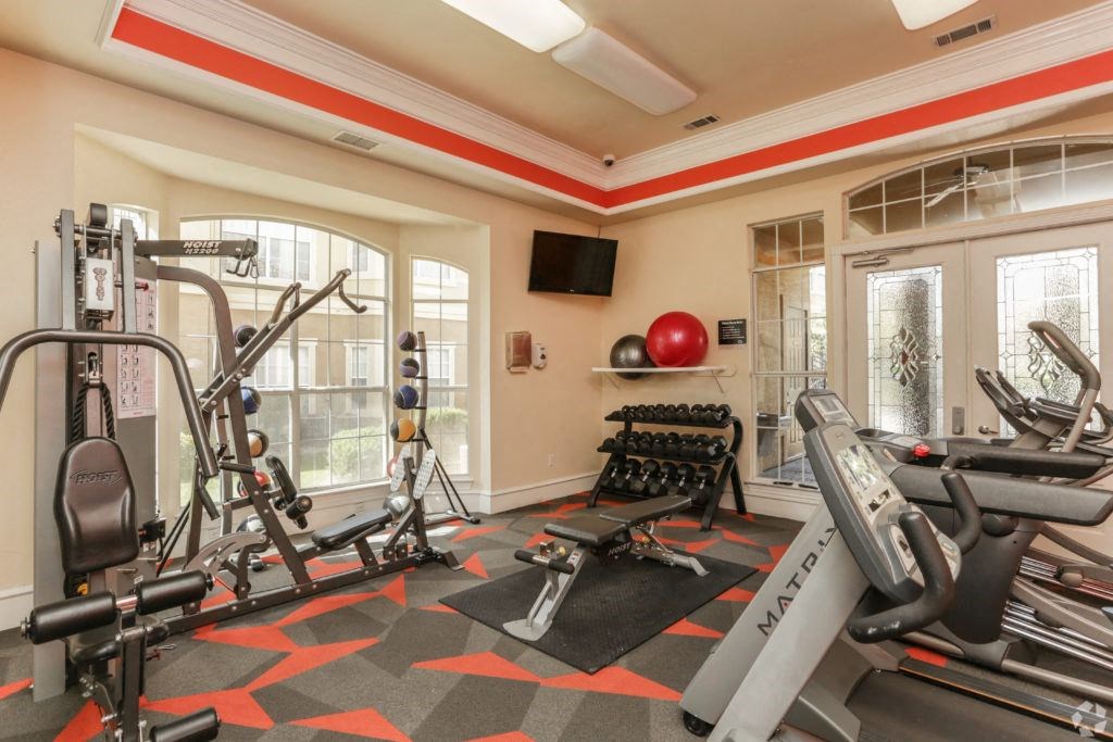 a gym with exercise machines and a tv on the wall