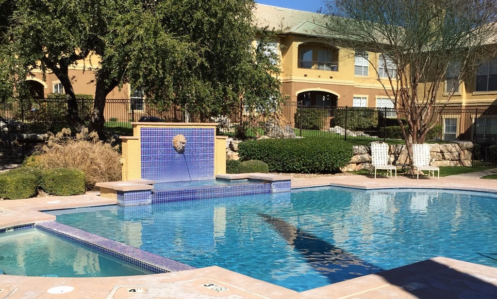 a swimming pool with a fountain in front of a house