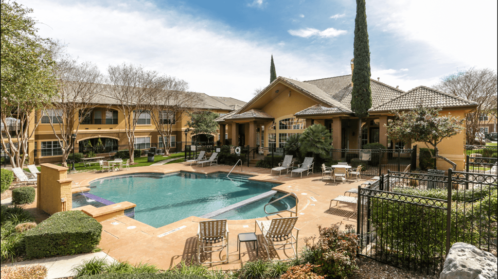 a swimming pool with chairs and a house in the background