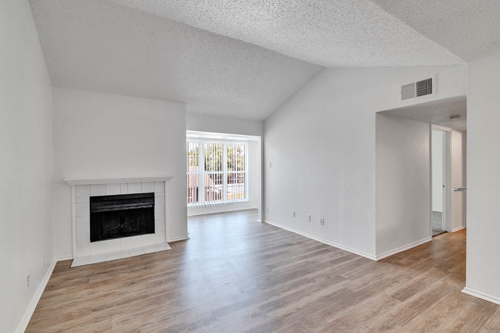 the living room and dining room of an apartment with a fireplace