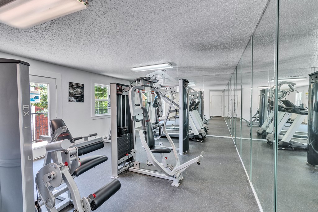 a gym with weights and mirrors on the floor and a glass wall