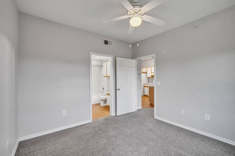 a bedroom with a ceiling fan and a door to a bathroom
