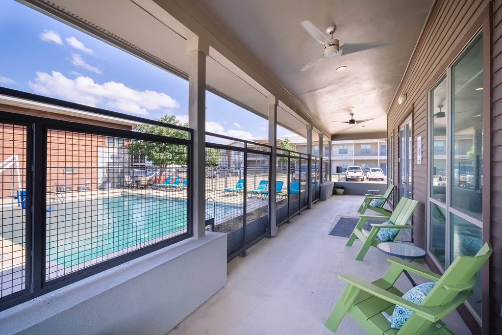a porch with green chairs and a swimming pool