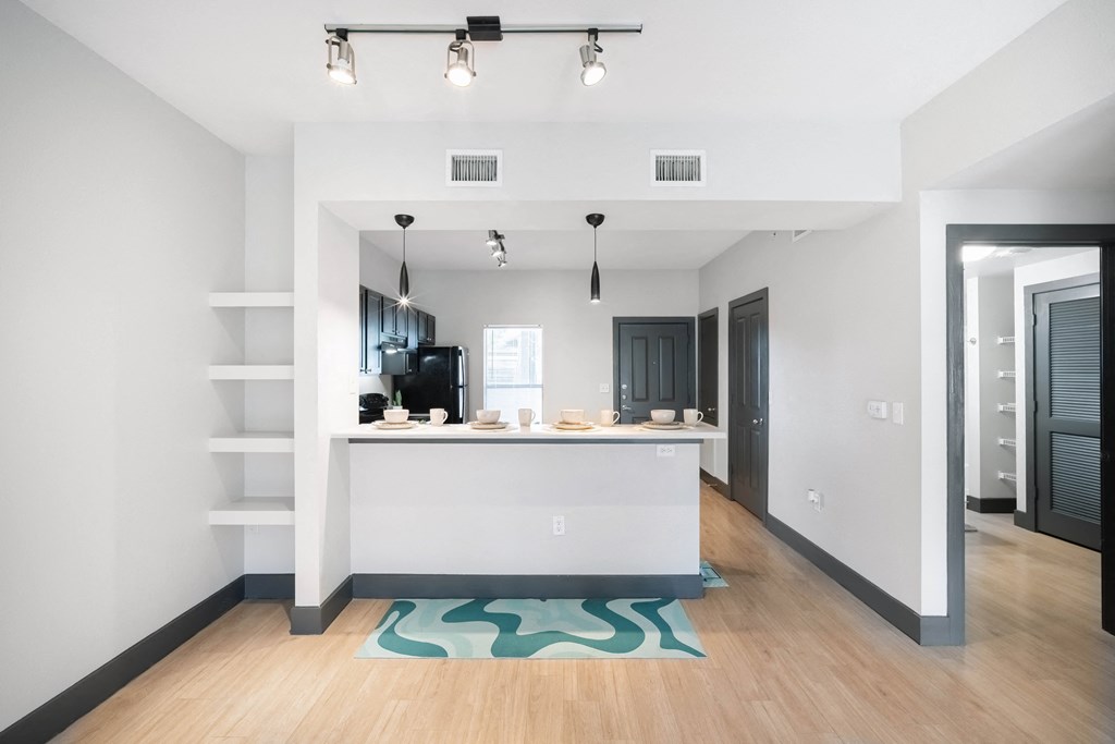 a kitchen and living room with white walls and wood floors