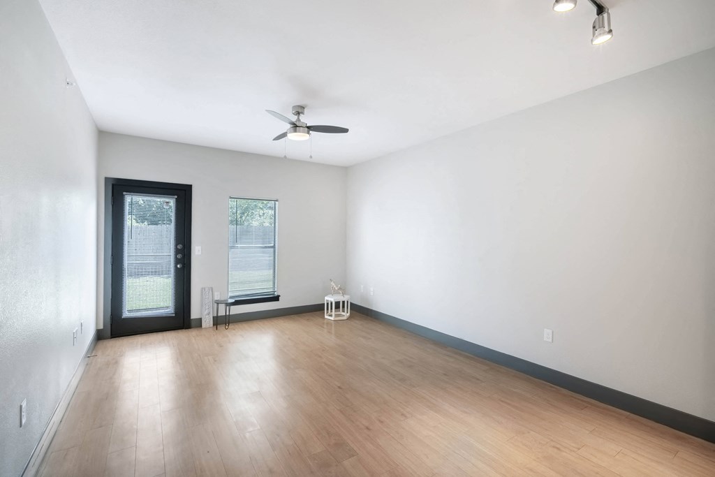 an empty living room with wood floors and a ceiling fan