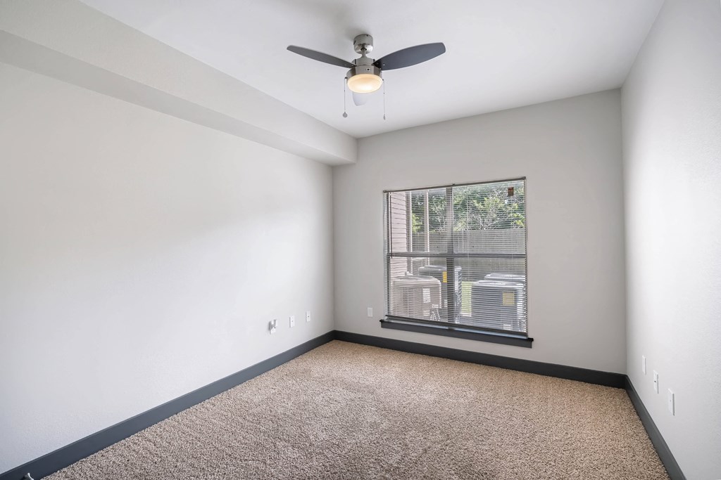 an empty room with a window and a ceiling fan