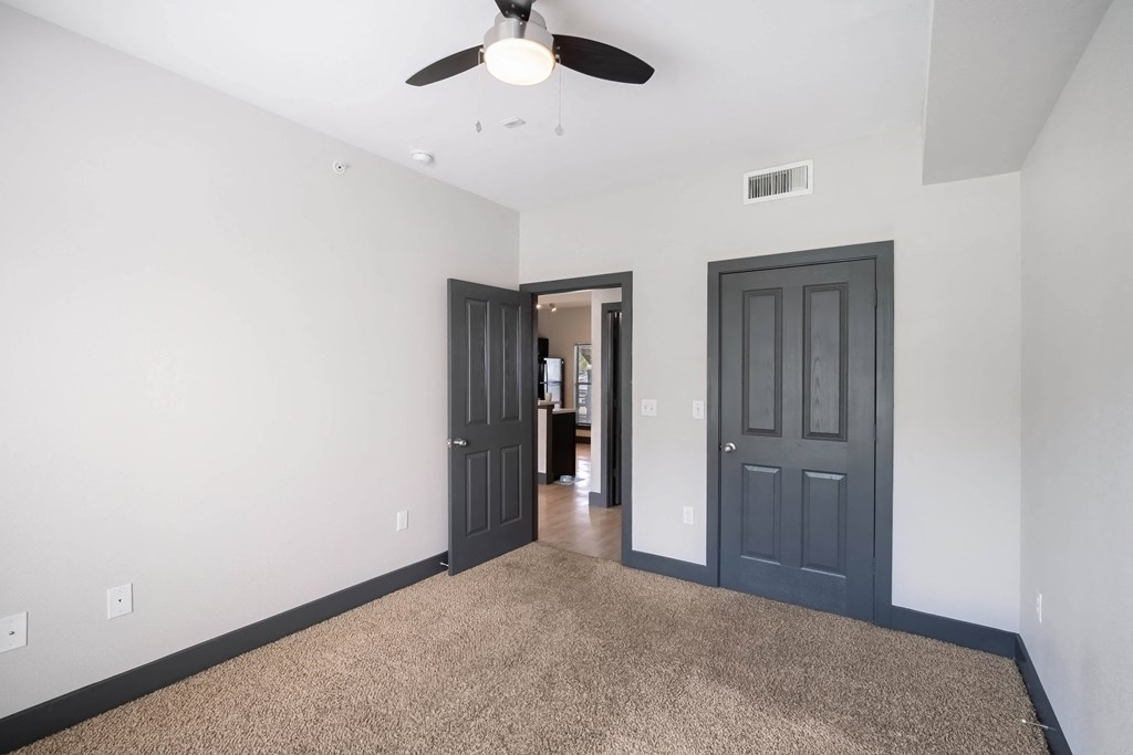 a empty room with a ceiling fan and a door to a hallway