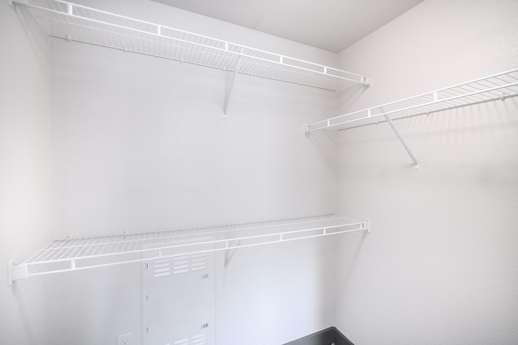 an empty closet with white walls and white shelves