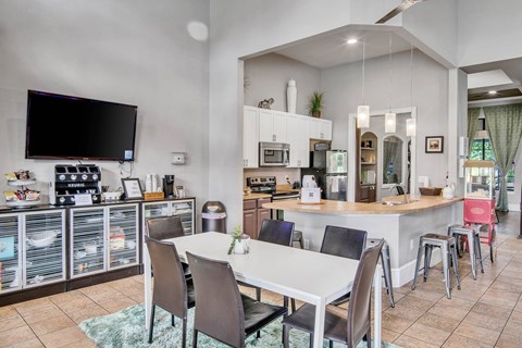 a dining room with a white table and chairs and a kitchen with a tv