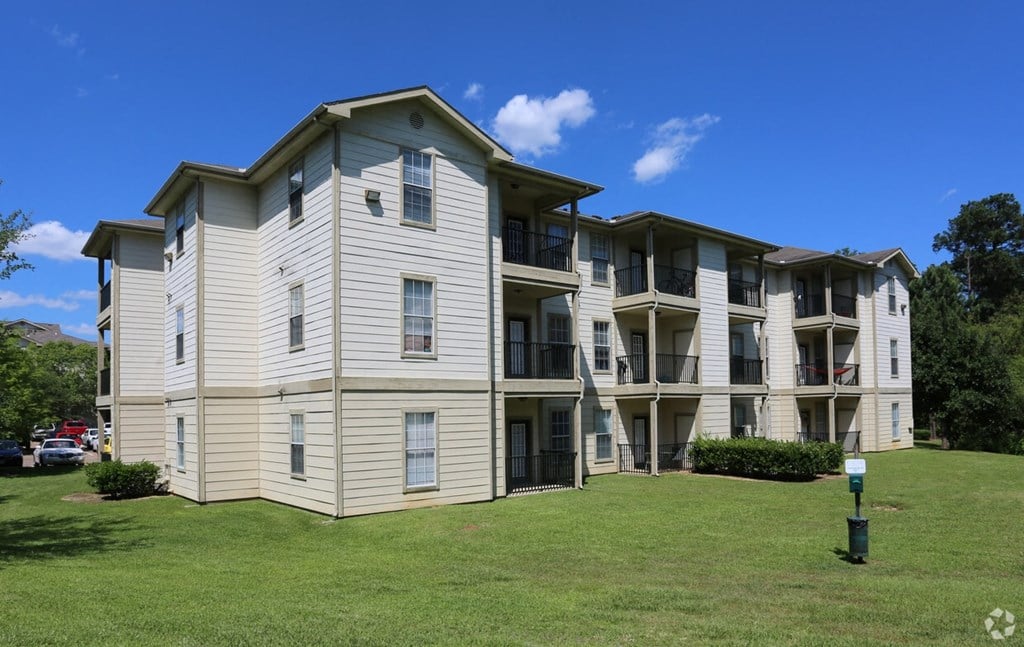 an apartment building on a grassy hillside with a blue sky in the background