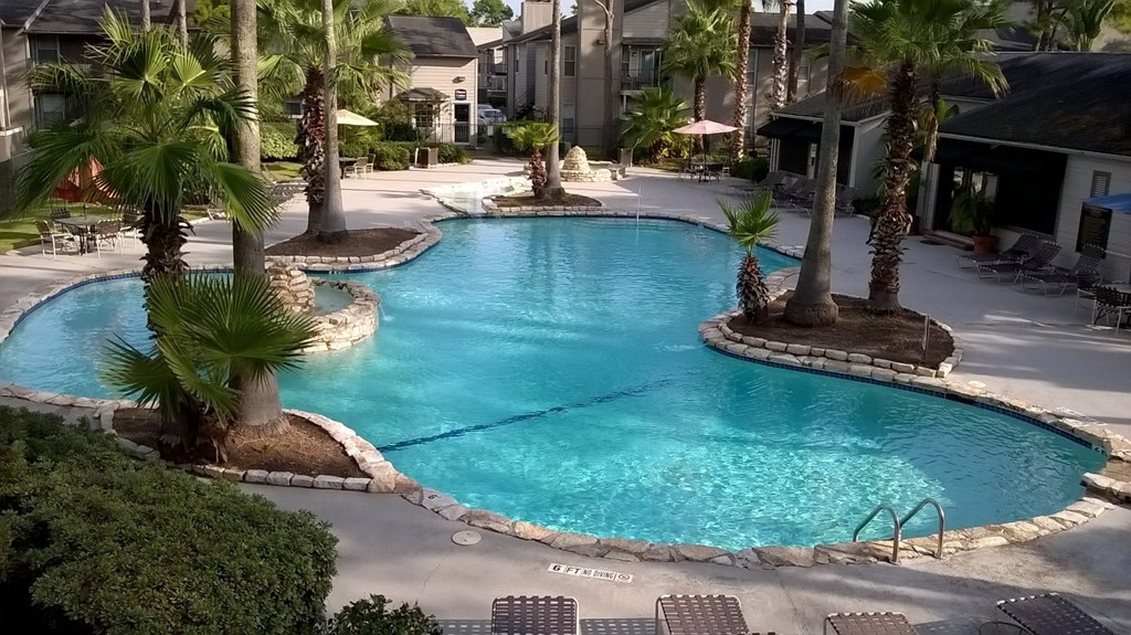 a large swimming pool with palm trees in front of a building