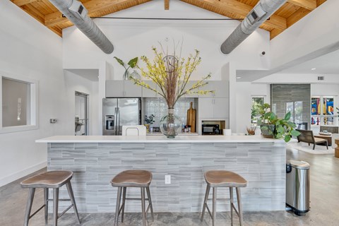 A modern kitchen with a stone counter and bar stools.