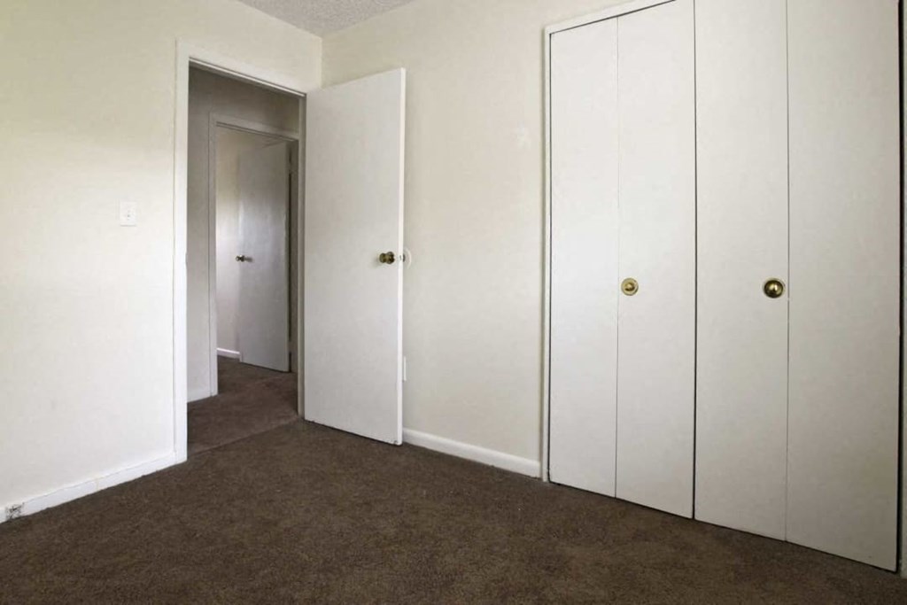 a carpeted room with three closets and a door to a closet