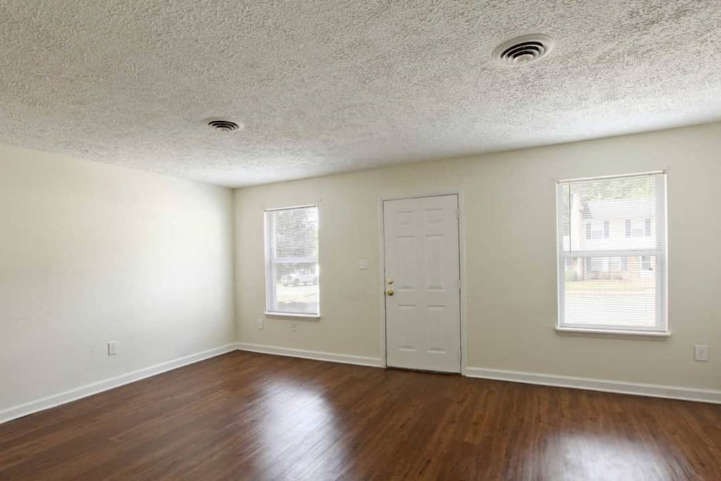 an empty living room with wood floors and a white door