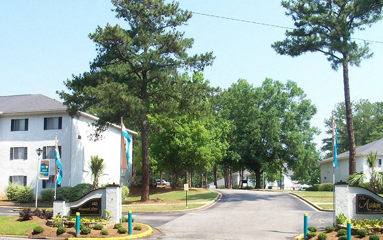 a street in front of a white building with trees