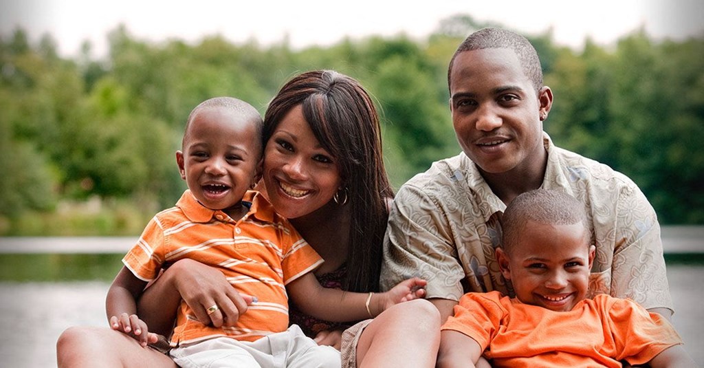 a family of four posing for a picture by a lake