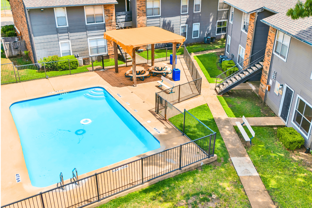 an aerial view of a swimming pool and a picnic table in front of a house