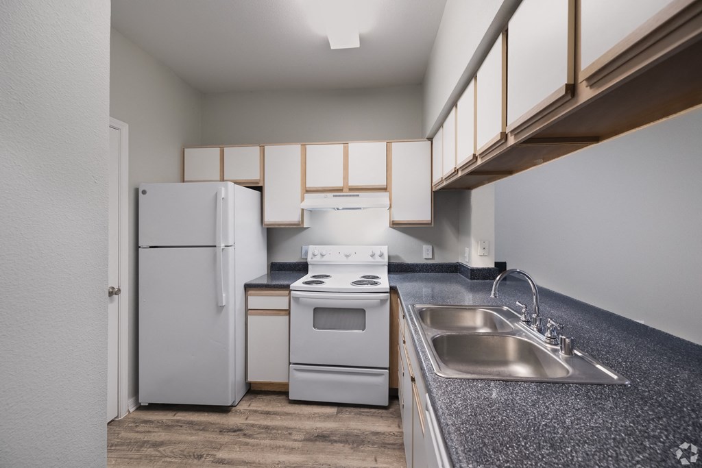 a kitchen with white appliances and a sink and a refrigerator