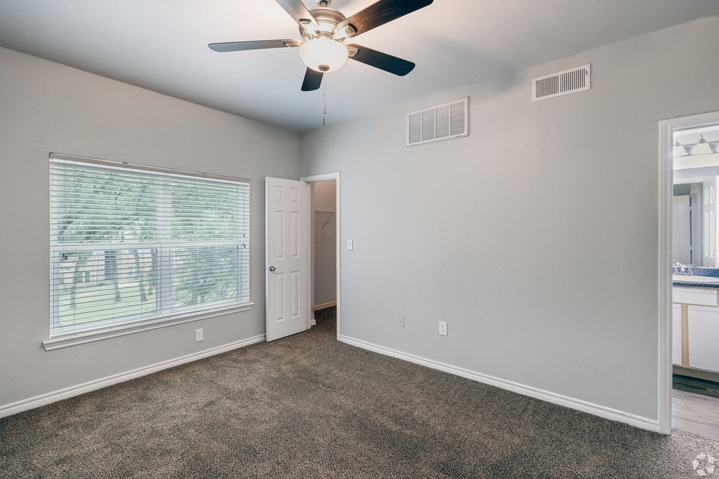 an empty living room with a ceiling fan and a window