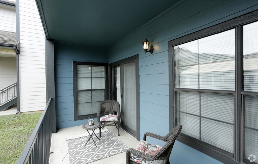 a covered porch with two chairs and a table