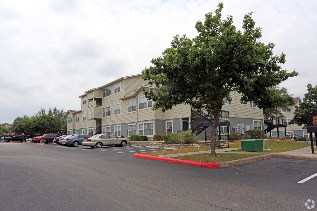 a row of apartment buildings with cars parked in a parking lot