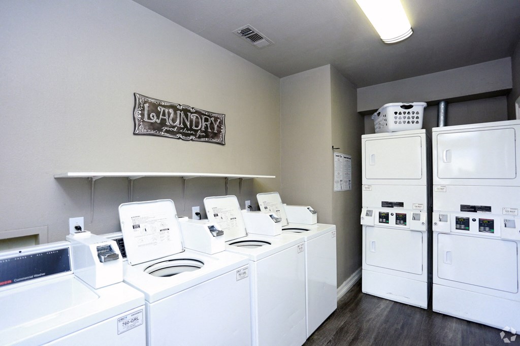 a room with a bunch of washes and dryers in it and a refrigerator