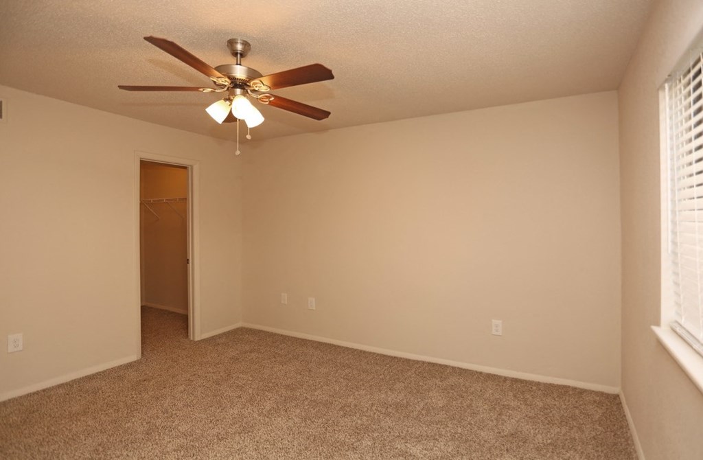 a bedroom with a ceiling fan and a door to a closet