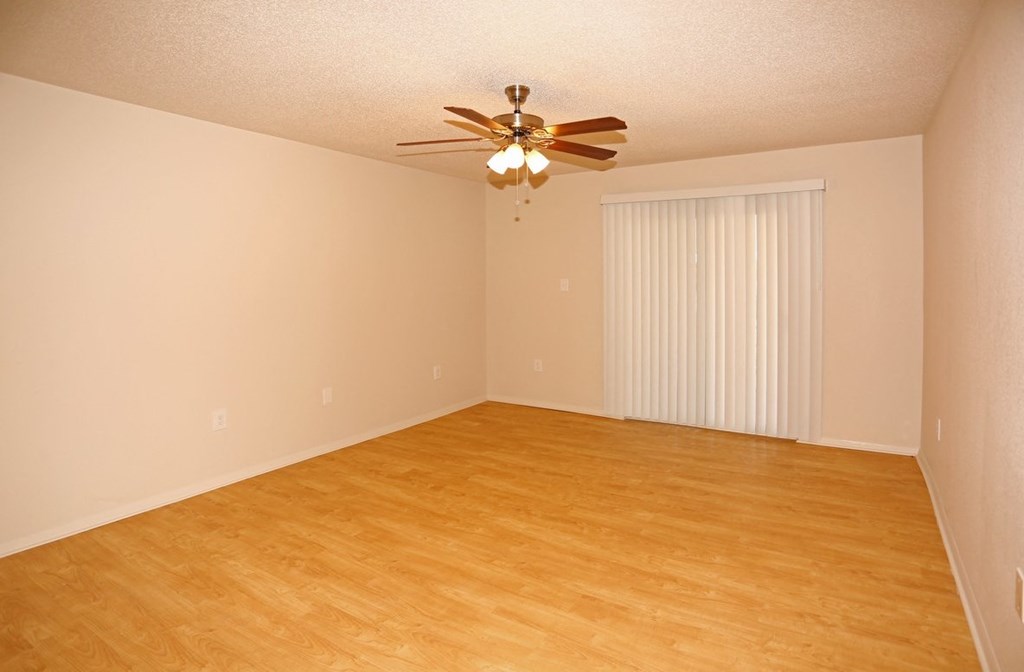 an empty living room with a ceiling fan