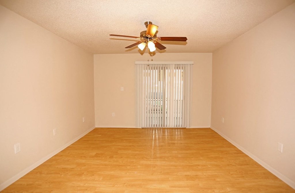 a empty living room with a ceiling fan and a window