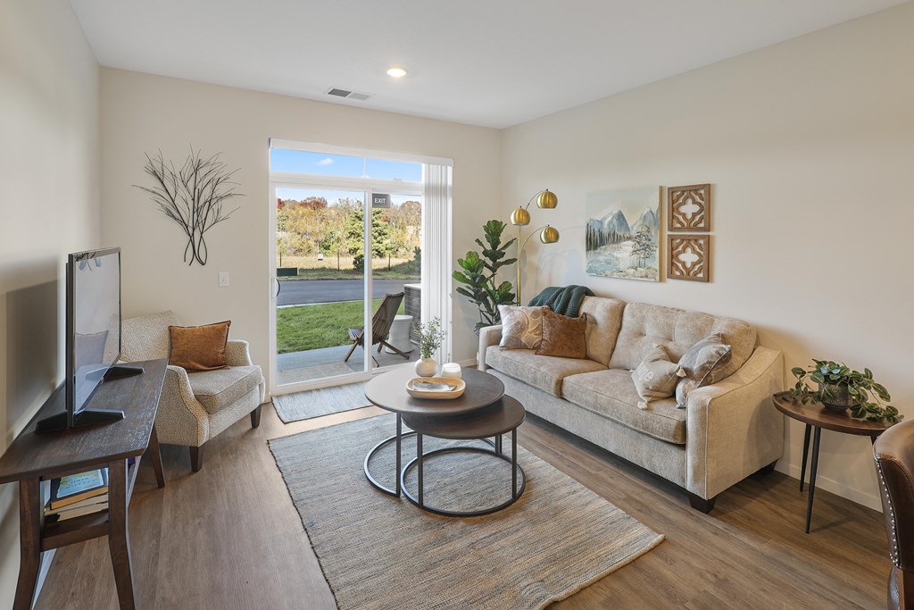 a living room with a couch and two chairs, a tv and large sliding glass doors leading outside