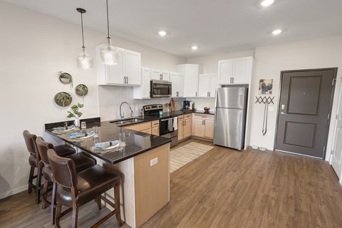 a kitchen with stainless steel appliances and a island with chairs
