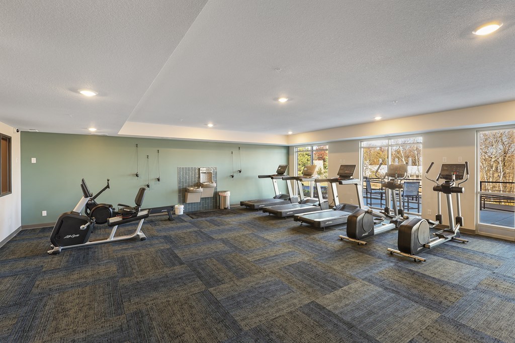 a gym with treadmills and other exercise equipment in a building with windows