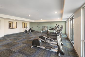 a gym with treadmills and other exercise equipment in a large room with windows