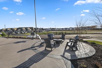 a patio with chairs and tables and a street with houses in the background