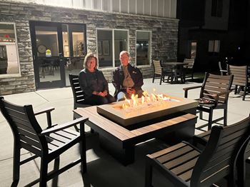 Two people sitting by a fire pit on a patio.
