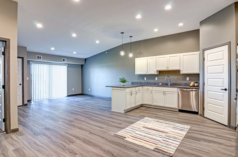 A kitchen with white cabinets and a striped rug on the floor.