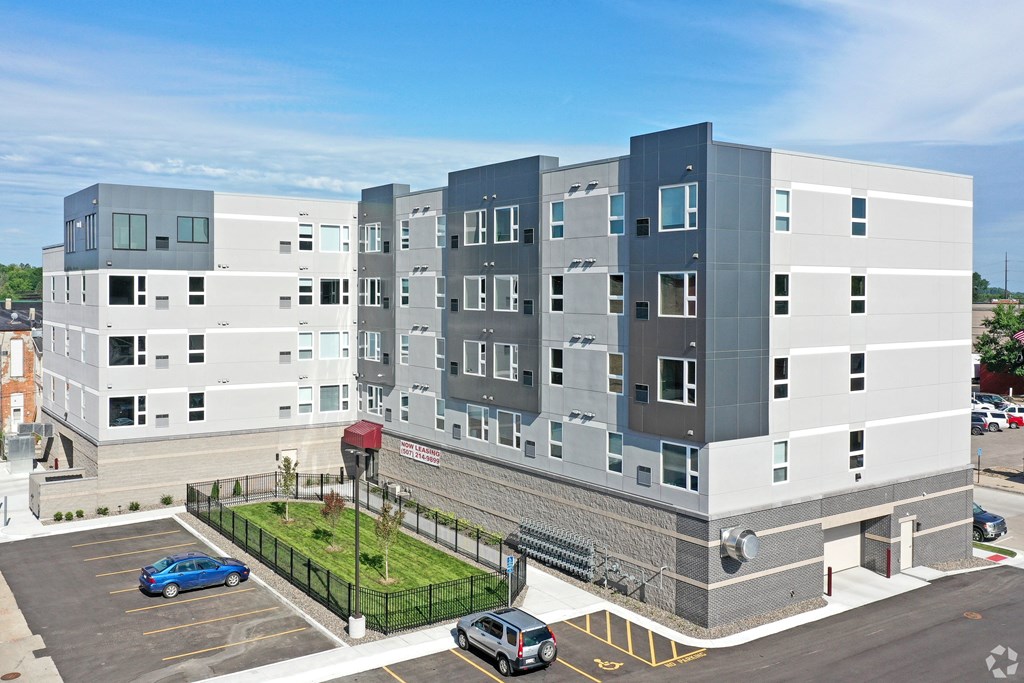A modern multi-story building with a parking lot in front.