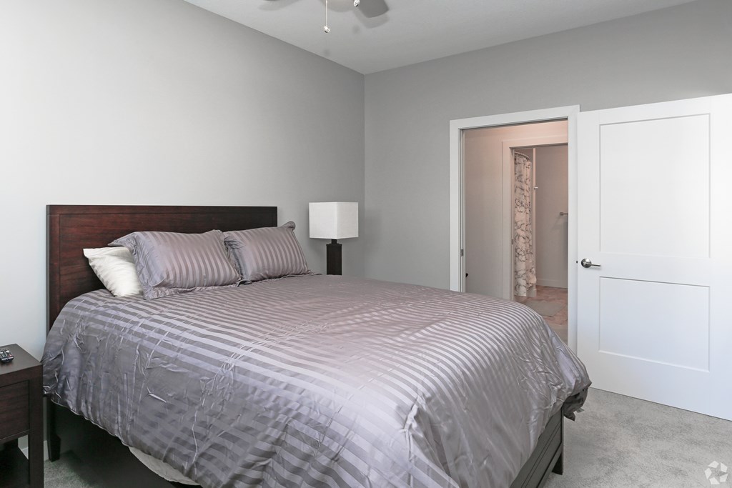 A bedroom with a bed, nightstand, and lamp.