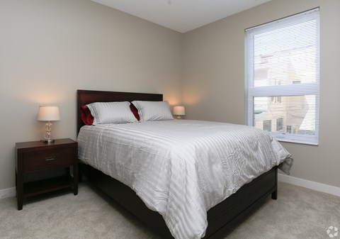 A bedroom with a bed, nightstand, and window.