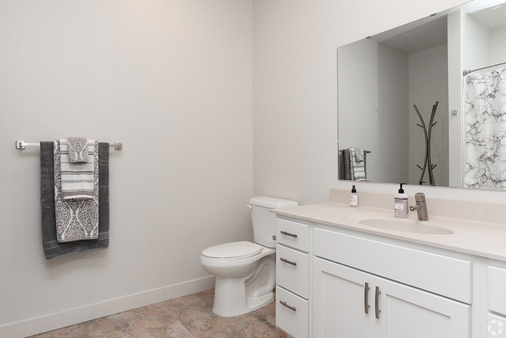 A white bathroom with a toilet, sink, and mirror.