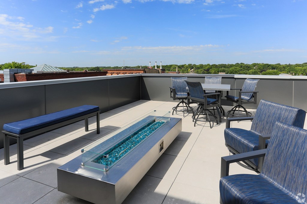 A rooftop patio with a hot tub and chairs.