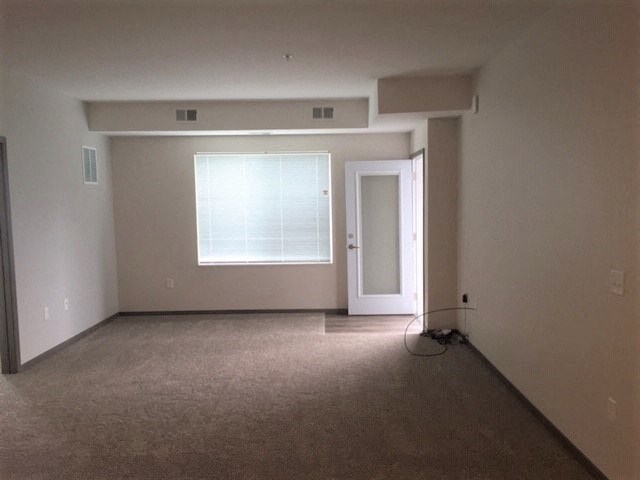 an empty living room with a door and a window