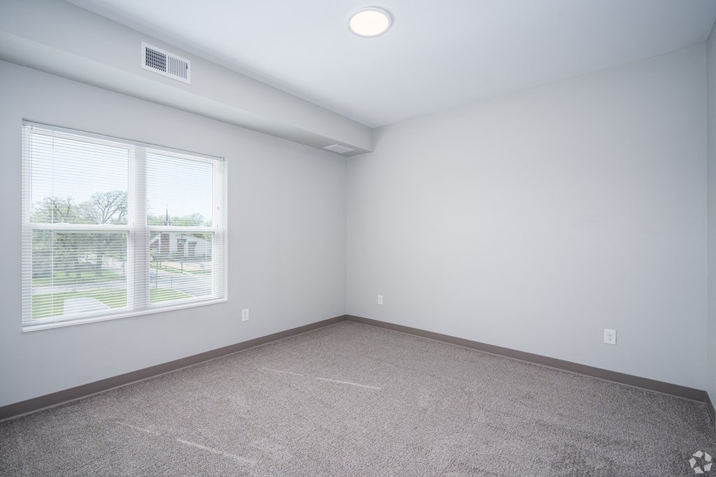 an empty room with a large window and carpet
