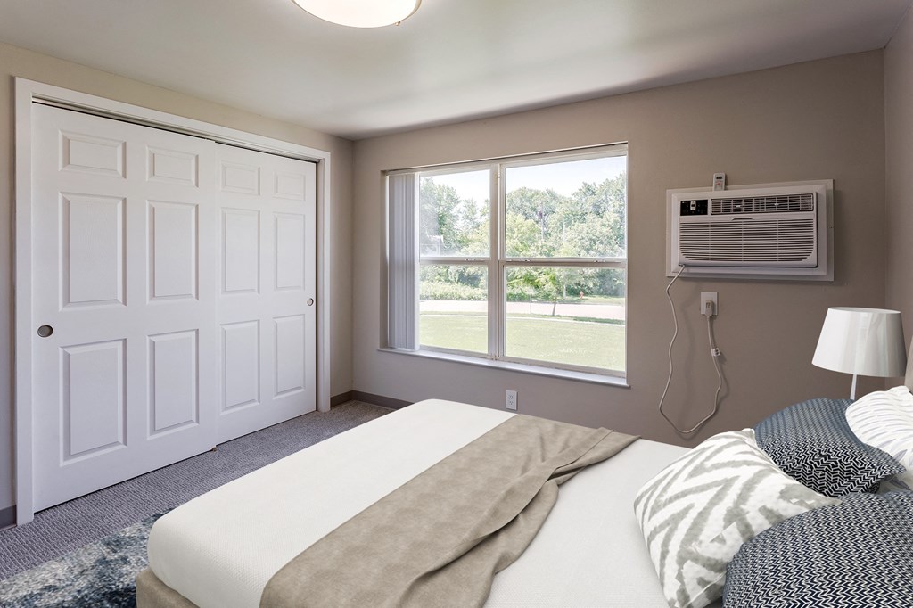 a bedroom with a bed and a window with an air conditioner