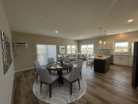 A dining room with a table set for six with a kitchen in the background.