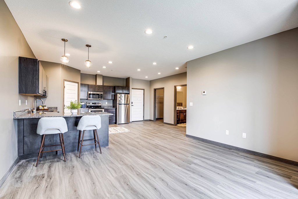 an open kitchen and living room with a kitchen island and bar stools
