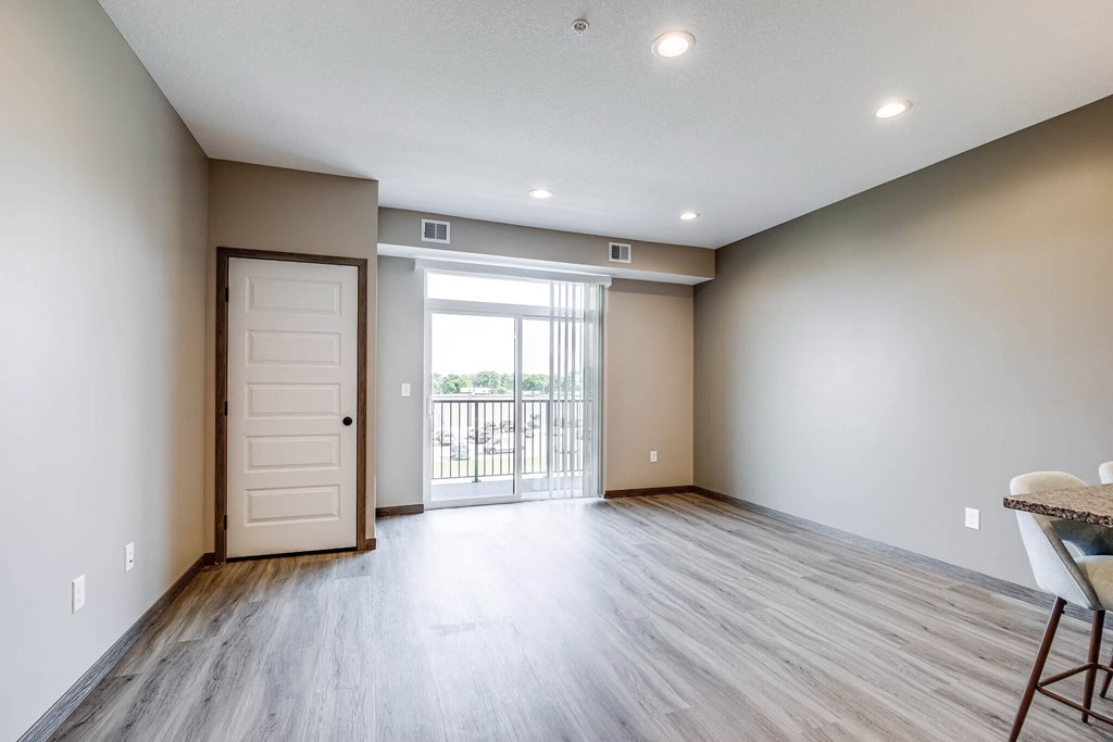 an empty living room with a door to a balcony