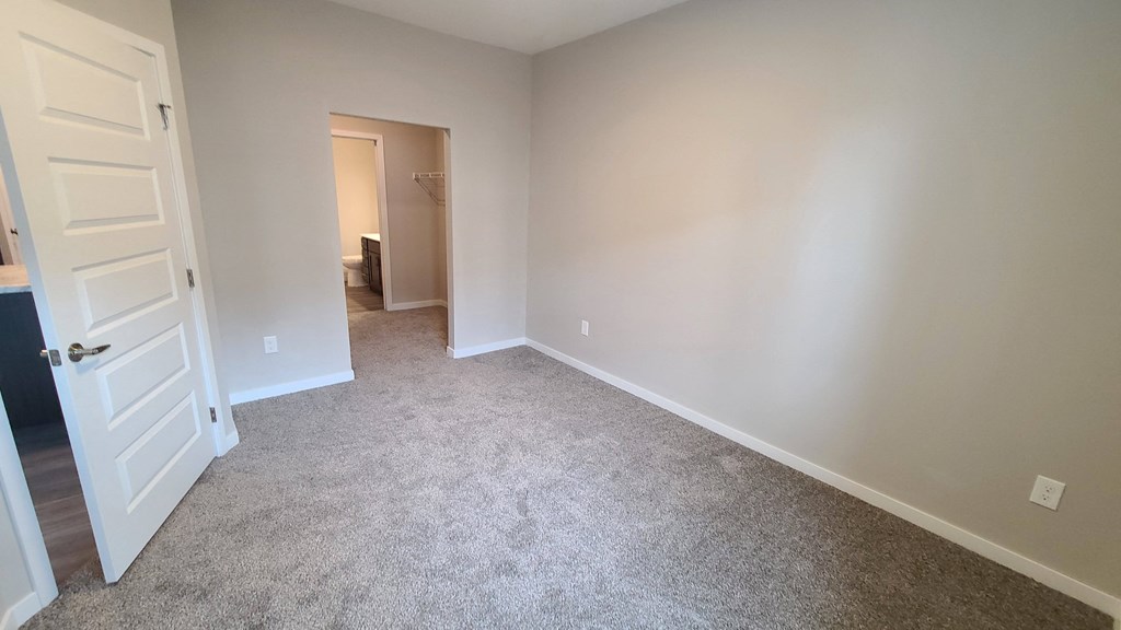 a bedroom with a carpeted floor and a white door
