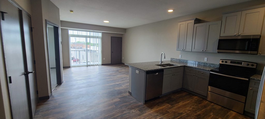 a kitchen and living room with a sliding glass door to a balcony