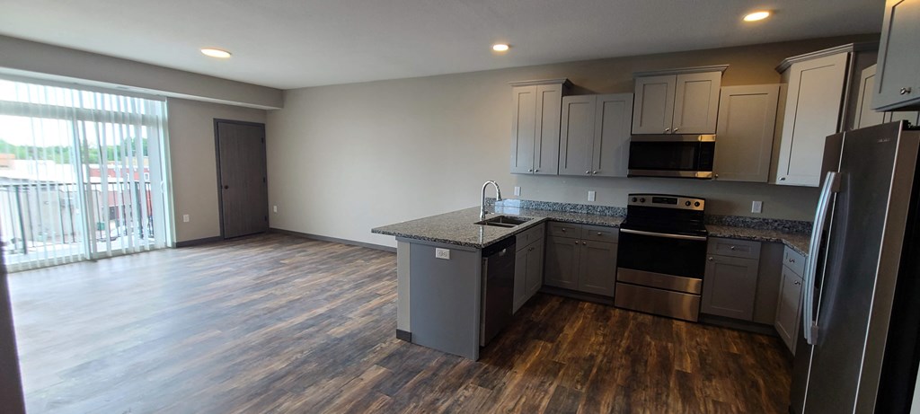 a kitchen and living room with wood floors and stainless steel appliances